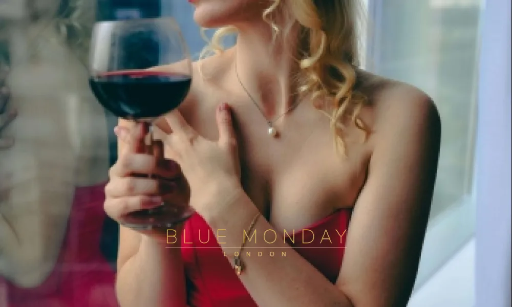 a high class escort in a red dress holding a glass of wine