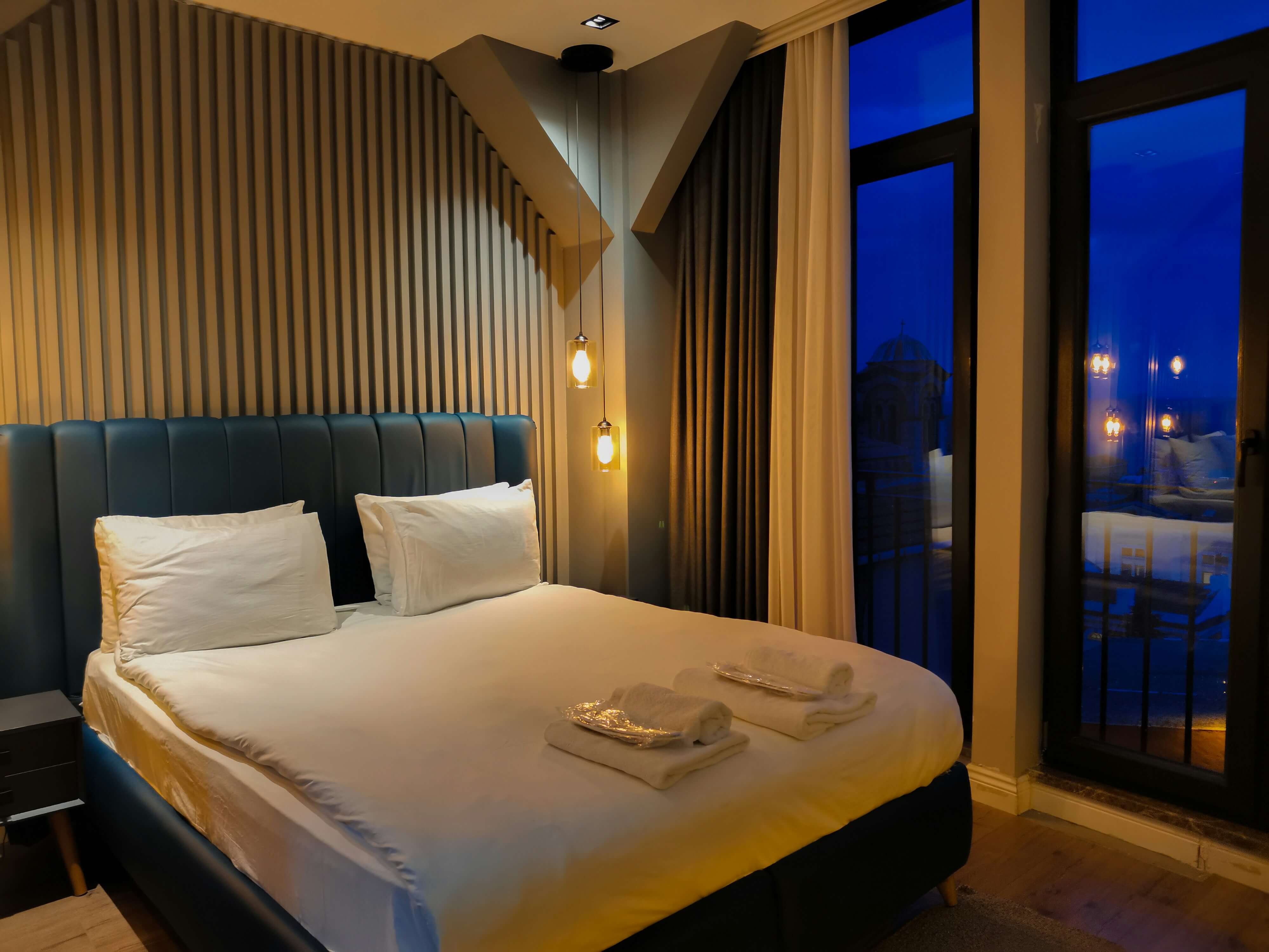 a hotel bed at night with two sets of folded towels
