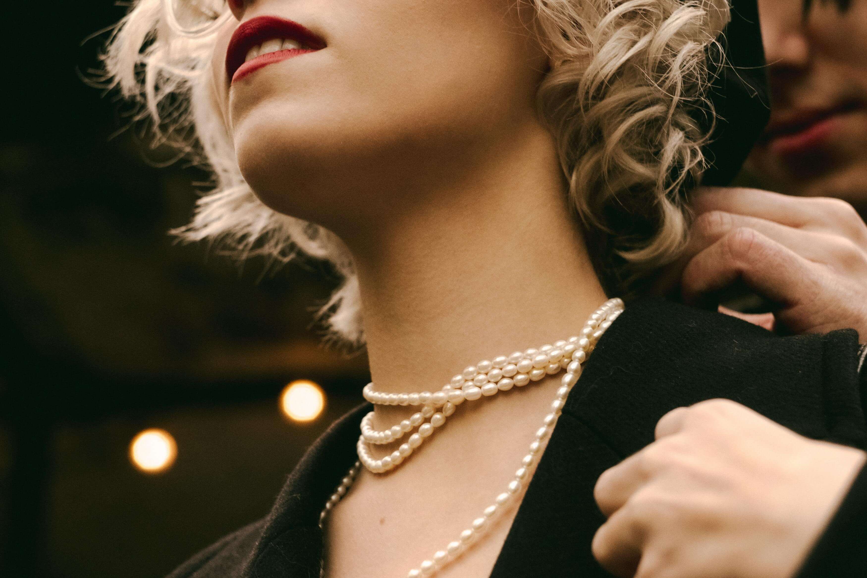 a client putting a pearl necklace on an escort