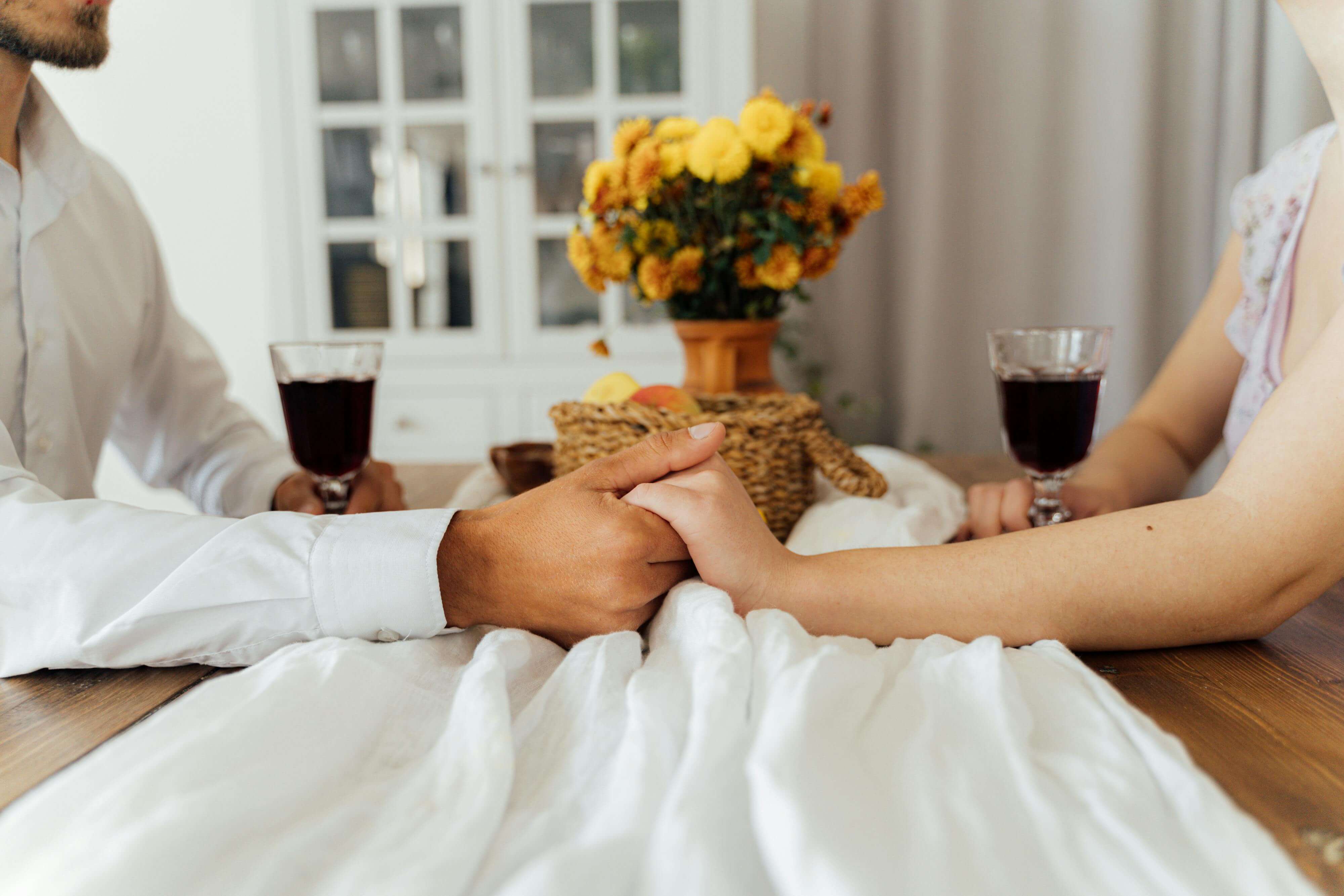 a man and a woman holding hands over a dinner table in a restaurant