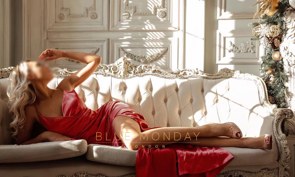 Bianca lounging on the sofa while wearing a red dress 