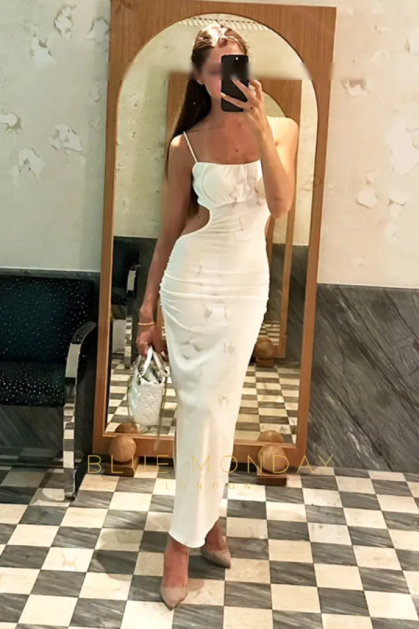 Lily taking a selfie in a long white dress with hip cutouts. She has a white hand bag.